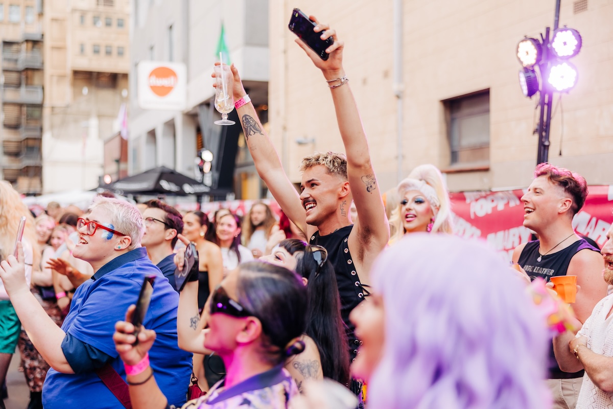 Festivalgoers cheering with hands in the air during the outdoor daytime Poppin Out block party in Adelaide, photographed by Samuel Graves.
